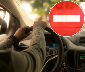 grafika przedstawia kierowcę trzymającego kierownicę i znak zakaz wjazdu